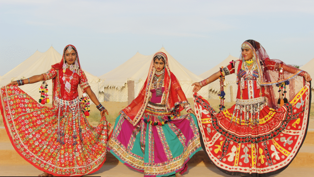 Kalbeliya folk dancers performing traditional Rajasthani dance at desert camp under starry sky