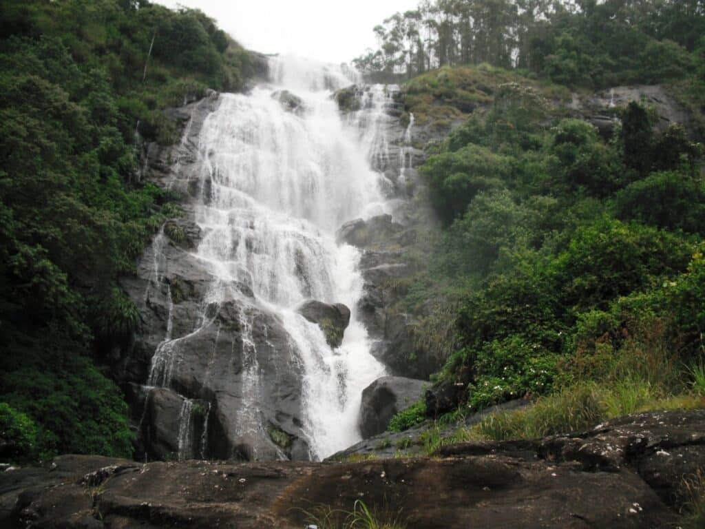 Chinnakanal Waterfall cascading down rocks amidst lush greenery near Munnar Kerala.