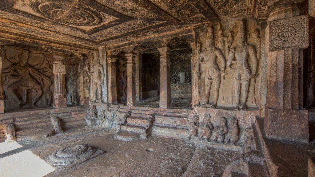 Interior of Ravana Phadi Cave Temple in Aihole, featuring detailed carvings of Nataraja and other deities.