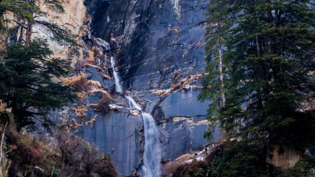 The serene Jogini Waterfalls cascading down a rocky cliff, a beautiful natural place to visit on a trek from Manali.