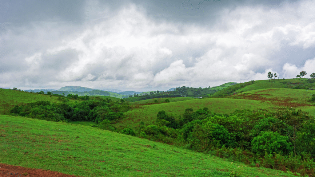 Vagamon's rolling green meadows with mist-covered hills and a lone traveler walking along a path. hidden gems of kerala