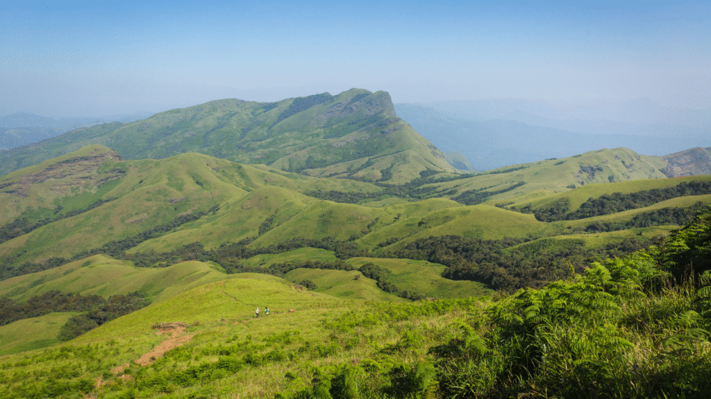 kudremukh, Breathtaking view of Kudremukh Peak surrounded by lush green hills and misty clouds.